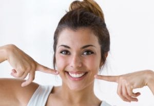 woman smiling and pointing to her cheeks