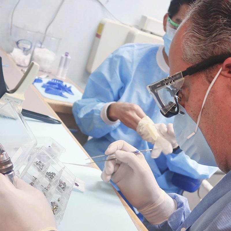 Dental implant specialist performing implant procedure with surgical instruments in clinic